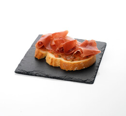 tostada de jamón serrano con tomate sobre plato de pizarra. tapa española