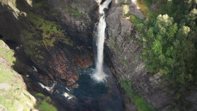Aerial view of the massive waterfall falling into a deep gorge. Orbit shot, slow-motion.