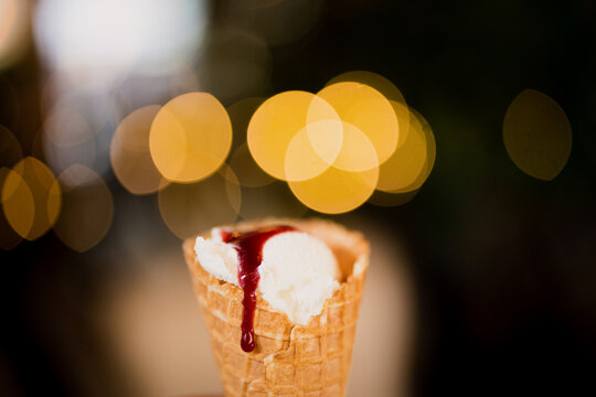 A gourmet ice cream with red sauce during the heatwave with colourful bokeh lights behind subject