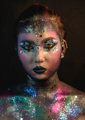 Creative make-up of a girl with rhinestones and piercing