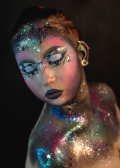 Creative make-up of a girl with rhinestones and piercing