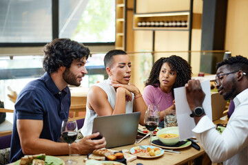 Businesspeople sit at the dinner table in a restaurant and brainstorm about a start-up project.