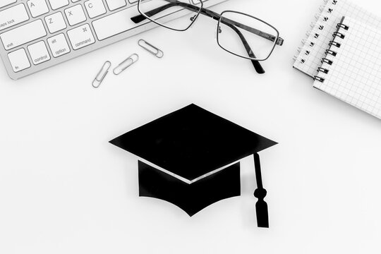 Graduation Hat On Students Table. Masters Or Bachelors Degree Concept