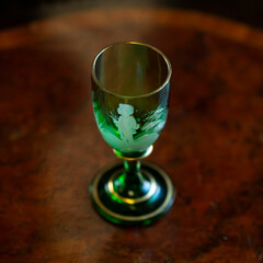 green glass wineglass in luxury interior. green glass with engraving close-up. bohemian glass closeup