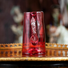 glass red mug in luxury interior. crystal cup with unusual handmade. bohemian glass closeup