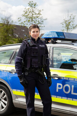 Polizistin weiblich vor Polizeiauto
