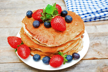 Pancakes with strawberries and blueberries on the table.