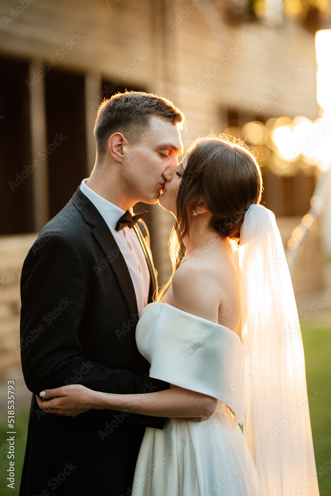 Wall mural young couple the groom in a black suit and the bride in a white short dress