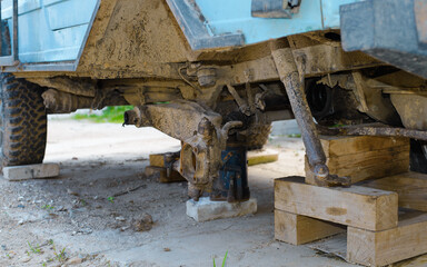 Repair of broken old car. Close-up of car without front wheel standing on sticks, outdoors