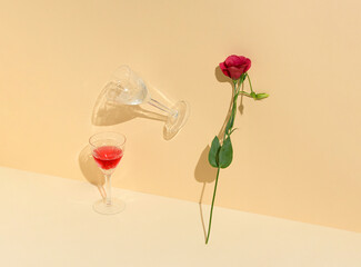 Creative composition with crystal wine glasses and  lisijantus. Red wine, bloom flowers, shadows and sunny day. Minimal concept on pastel beige background..