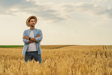 Happy farmer is standing in his growing wheat field.	