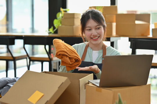 Asian Women Using Laptop Live On Social Media For Presenting A Shirt And Selling.