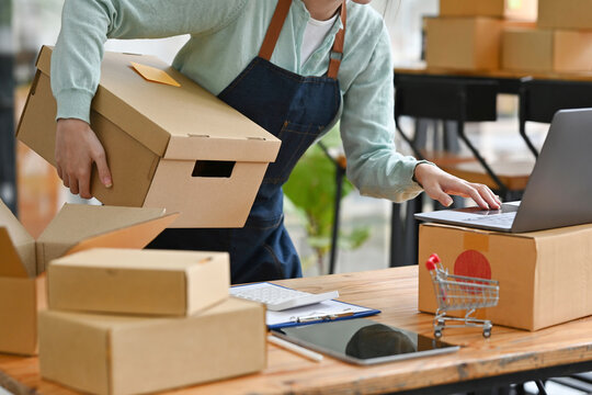 Startup small business SME, Entrepreneur owner using laptop checking online purchase shopping order to preparing sending product box.