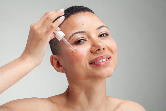 Portrait�of smiling woman applying serum on cheek - Image of skin care, Vitamin C serum