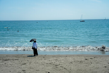 海辺に日傘をさす女性