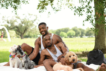 USA, Louisiana, Portrait of gay couple with dogs having picnic on lawn in park