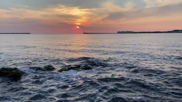 Beautiful sunset on the embankment of Sevastopol (Crimea). The sun sets in the sea. Very beautiful seascape, view of the sea, waves and sky with clouds