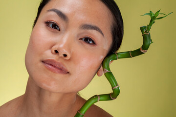 Studio portrait of woman with green bamboo twig