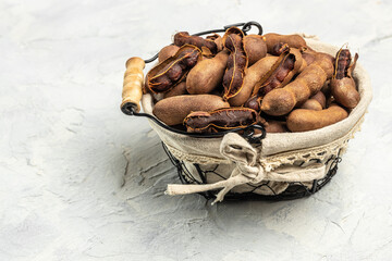 Delicious ripe tamarinds on a basket on a light background, exotic fruit. banner, menu, recipe place for text, top view