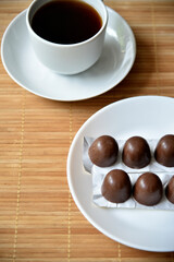 Tea couple on a mat with chocolate bars. A porcelain cup and saucer and tea with sweets.