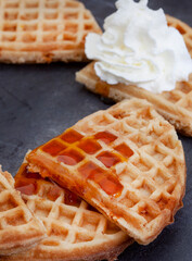 Waffles with syrup and cream on black slate with copy space