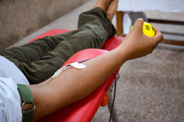 Blood donor at Blood donation camp held with a bouncy ball holding in hand at Balaji Temple, Vivek Vihar, Delhi, India, Image for World blood donor day on June 14 every year, Blood Donation Camp