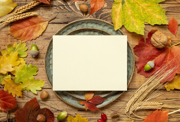 Autumn rustic table setting with blank card between leaves and berries top view, mockup