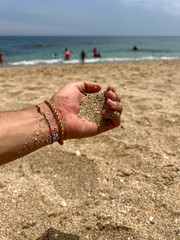 Male hand pouring beach sand on the beach