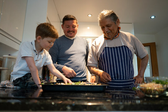 Senior man with son and grandson making pizza together - Powered by Adobe