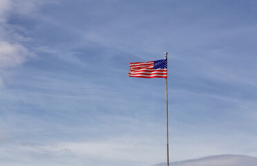 American Flag on the Cloudy Blue Sky background.