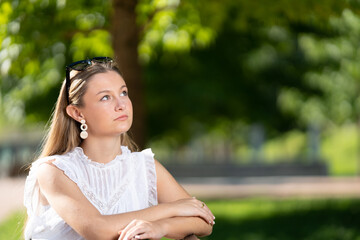 Portrait of young woman daydreaming and looking at copy space outdoors in a park. Teenager girl planning future