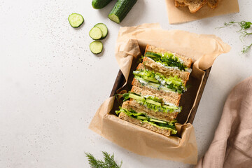Homemade English tea cucumber sandwiches with ricotta and dill on white background. Top view. Copy...