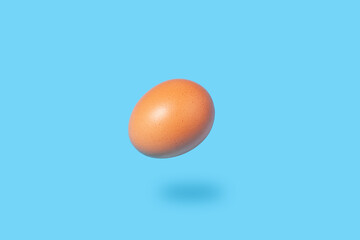 brown chicken egg floats in the air on a blue background - creative image