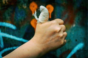 hand showing thumb up, ok, all right getsure sign on painted wall background. Nice symbol of gesture with knuckle and bandage big finger up