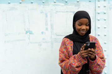 Smiling young woman wearing hijab looking at smart phone © Cultura Creative