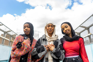 Portrait of smiling young women wearing hijabs holding hands