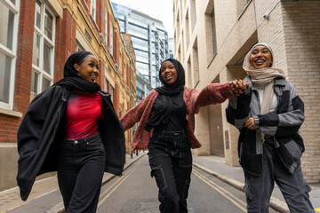 Fototapeta na wymiar Three young women wearing hijabs walking in city
