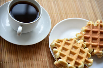 Tea couple with Viennese waffles on a mat. Tea party with waffles. A porcelain cup and saucer on a mat.
