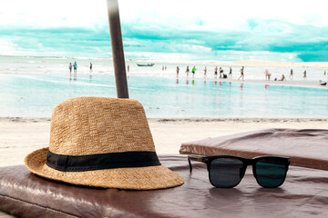Hat and sunglasses on a beach chair with the sea in the background and blue sky. Brazilian beach....