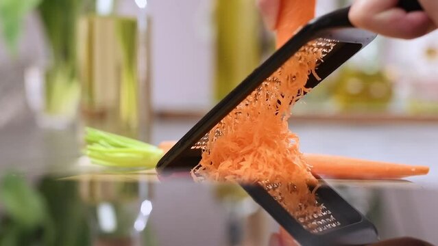 Grating carrot with a grater in the kitchen.
