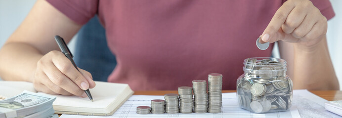 Woman are taking notes on household income and expenses and working to save money for future use,...