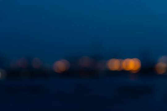 Blurred of industry background with defocused cargo dock terminal in sea with colorful bokeh lights at midnight. Urban and industry backdrop