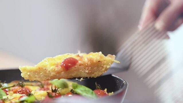 Chef serves spaghetti frittata with cherry tomatoes.
