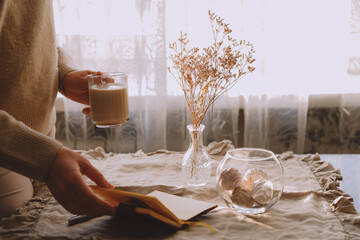Woman drinking morning coffee and checking her phone.
