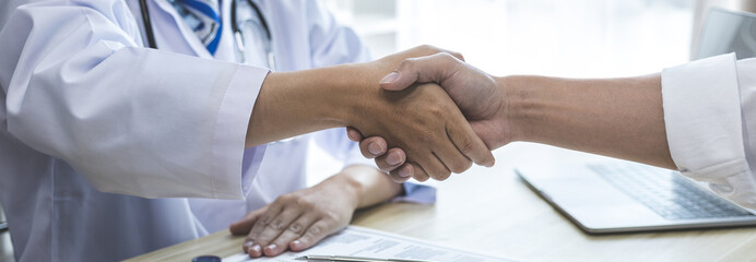 Obraz na płótnie Canvas Doctor shake hands to congratulate the patient who came to treat the sick and recovered normally. Congratulations between doctor and patient, Medical treatment and health check.