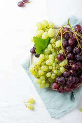 Red and yellow grape on the white linen tablecloth