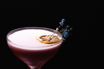 Close-up of a cocktail. Garnished with dried orange and colored. Black background