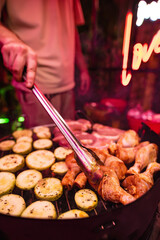 Close-up of a barbecue on the restaurant's summer terrace. Chicken legs and vegetables on fire