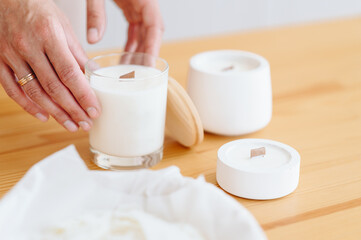 Group of White Candles Stand on Wooden Table. Women's h\Hands with Ring Hold Candle Close-up.