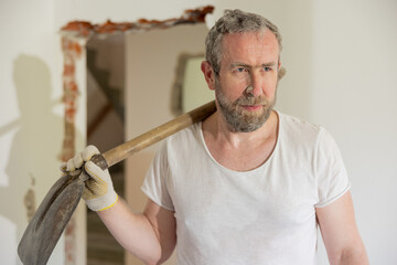 Portrait of a man dusty all soiled in dust. The man with gray hair and beard has a shovel on his...
